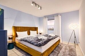 A hotel room with a bed, bedside tables, a lamp, and a floor lamp. - Holiday apartment with 2 bedrooms (Westerland)