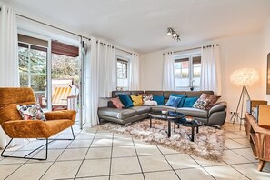 A modern living room with a sectional sofa, a single armchair, and a coffee table. - Holiday apartment with 2 bedrooms (Westerland)