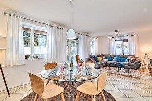 A modern living room with a glass dining table, a sofa, and a coffee table. - Holiday apartment with 2 bedrooms (Westerland)