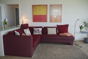 A living room with a red sofa set, a glass coffee table, and two abstract paintings on the wall. - Strandpalais, Apt. 508 (Cuxhaven)