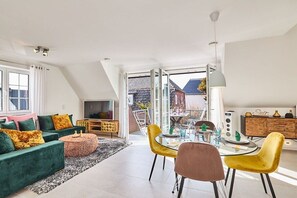 A modern living room with a sofa set, a dining table with chairs, and a television. - Holiday apartment with 3 bedrooms (Westerland)