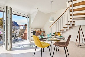 A dining area with a glass table, two chairs, and a modern staircase. - Holiday apartment with 3 bedrooms (Westerland)