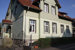 A two-story building with a traditional design, featuring a front entrance with a gate and steps leading up to it. - Holiday apartment with 1 bedroom (Wernigerode)