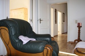 A room with a leather armchair, wooden cabinet, and a small table with a candle. - Holiday apartment with 1 bedroom (Wernigerode)