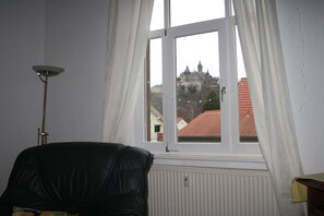 A room with a large window, a radiator, and a black leather chair. - Holiday apartment with 1 bedroom (Wernigerode)