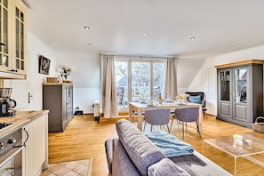 A modern kitchen with a dining area, a sofa, and a view through a large window. - Holiday apartment with 3 bedrooms (Morsum)