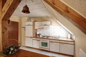A kitchen with white cabinets, a stove, and a sink. - Siewertsen Apt. No. 1 (Alkersum)