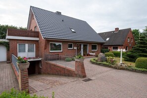 A residential house with a sloped roof, brick exterior, and a paved driveway. - Siewertsen Apt. No. 1 (Alkersum)