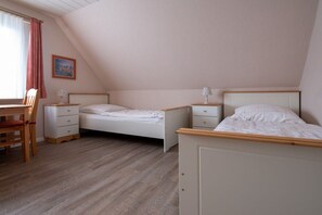 A bedroom with two single beds, a desk, and a chair. - Siewertsen Apt. No. 1 (Alkersum)