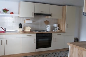 Een keuken met witte kasten, een zwarte oven, een koffiezetapparaat en een houten aanrecht.