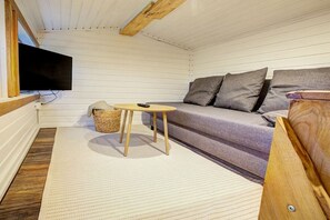 A cozy room with a sofa, a television, and a small table. - Holiday home with 1 bedroom (Westerdeichstrich)