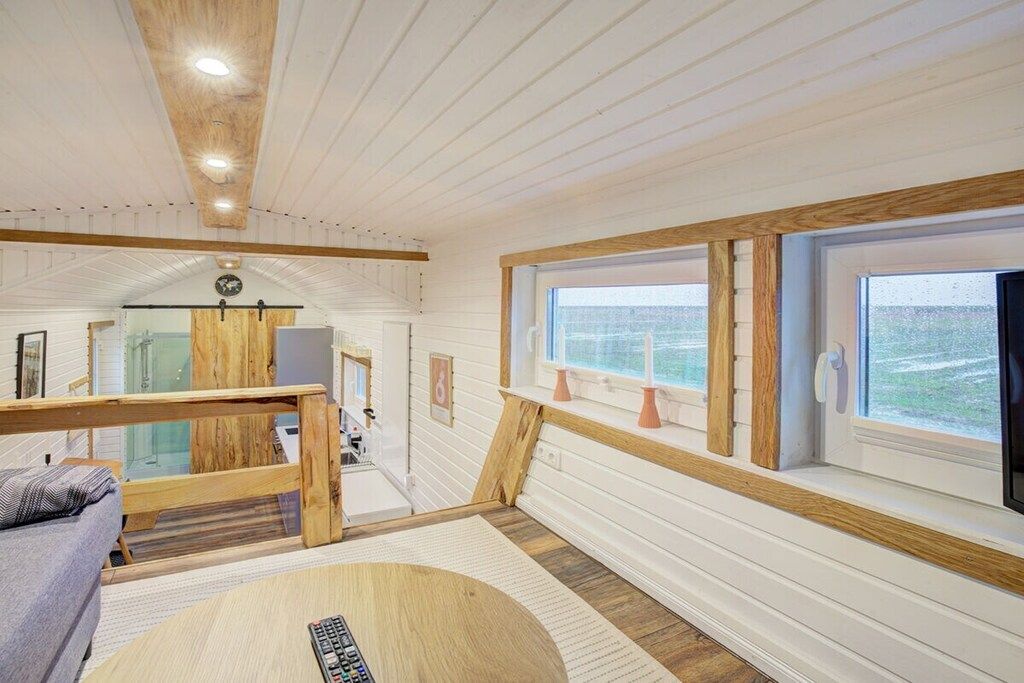 Une pièce avec un plafond en bois, une grande fenêtre donnant sur un beau paysage, une table ronde et un canapé.