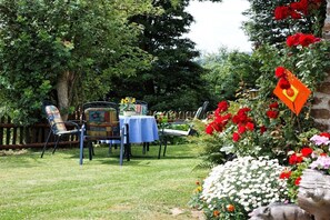 An outdoor dining area with a table set for two, surrounded by chairs and a decorative tablecloth. - Holiday apartment with 1 bedroom (Zwiesel)