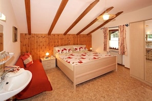 A bedroom with a bed, bedside tables, a nightstand, a window with curtains, a radiator, and a wardrobe. - Holiday apartment with 1 bedroom (Zwiesel)