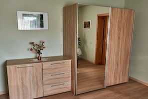 A room with a wooden wardrobe, a small cabinet, and a mirror. - Holiday apartment with 1 bedroom (Röslau)