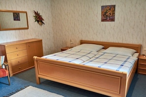 A bedroom with a wooden bed, a nightstand, a dresser, and a mirror. - Holiday apartment with 1 bedroom (Röslau)