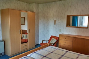 A bedroom with a bed, a wardrobe, a chair, and a small desk. - Holiday apartment with 1 bedroom (Röslau)