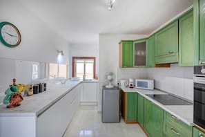 A modern kitchen with white cabinets, a green accent wall, a built-in oven, a microwave, and a sink. - Spacious & bright apartment, sun terrace PGAL1-1 (Sliema)
