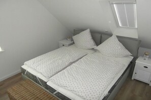 Quarto com uma cama, duas mesas de cabeceira, uma janela e um pequeno banco.