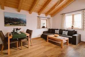 A cozy living room with a wooden ceiling, a dining table with chairs, a sofa, and a coffee table. - House at Kramer Holiday Apartment Kramer (Garmisch-Partenkirchen)