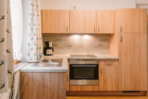A compact kitchen with wooden cabinets, a stainless steel sink, and a built-in oven. - House at Kramer Holiday Apartment Kramer (Garmisch-Partenkirchen)