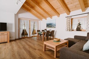 Une pièce avec un plafond en bois, un coin repas comprenant une table et des chaises, un canapé et un téléviseur.