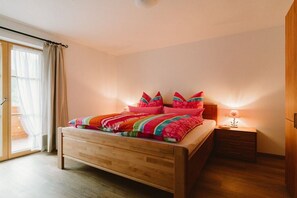 Une chambre à coucher avec un lit en bois, une table de chevet et une fenêtre avec des rideaux.