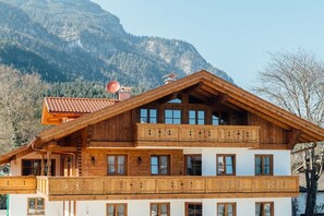 A multi-story wooden chalet with balconies, set against a mountainous backdrop. - House at Kramer Holiday Apartment Kramer (Garmisch-Partenkirchen)