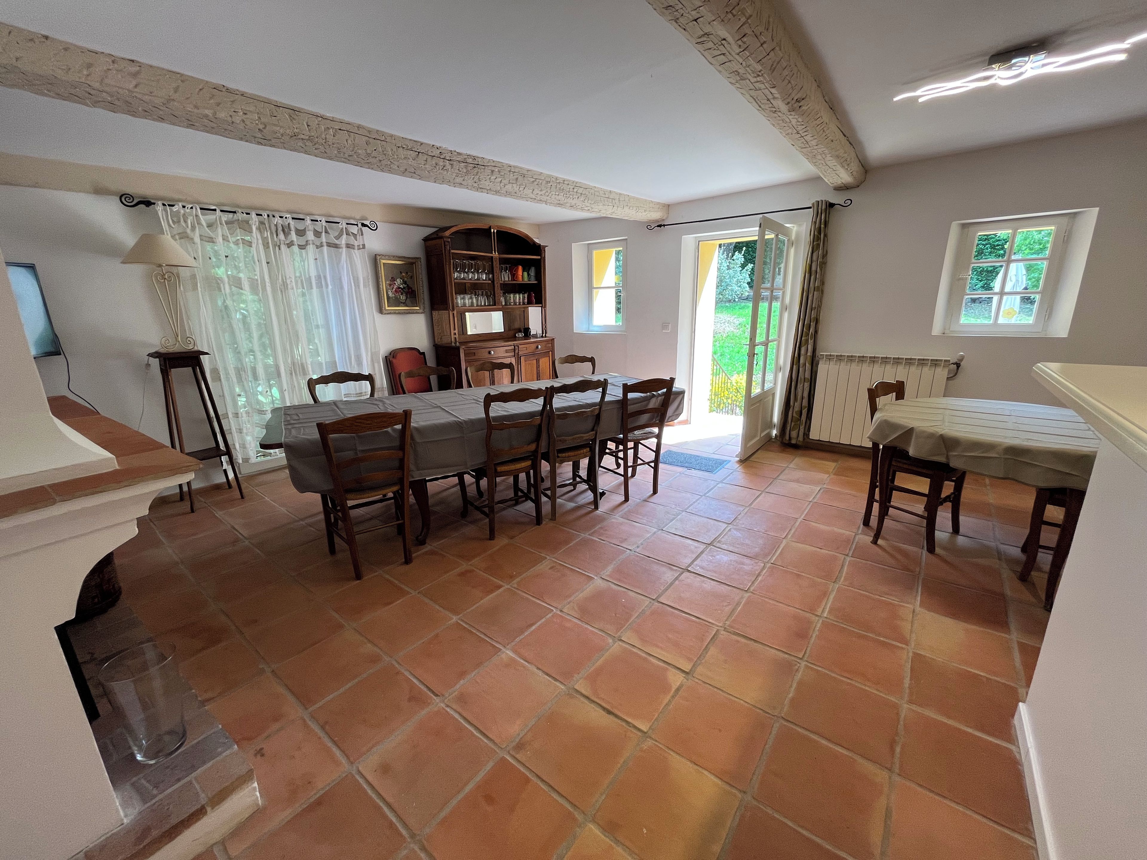 A dining area with a large table, chairs, and a cabinet.