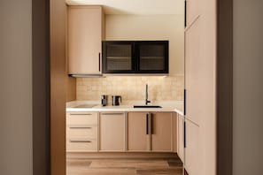 A modern kitchen with light wood cabinetry, a black range hood, and a tiled backsplash. - Beldersoy Resort & Spa, Part of Destination by Hyatt (Chimgan)