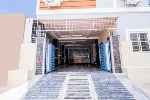 A building entrance with a tiled roof, a staircase leading up to the door, and a security gate.