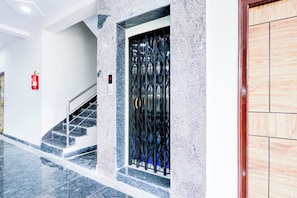A modern interior with a staircase, a fire extinguisher, and a security gate.