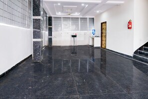Um lobby limpo e moderno, com piso de mármore, bebedouro e extintor de incêndio na parede.