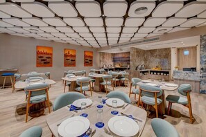 A dining area with round tables, chairs, and a bar area. - Kingsgate Hotel Clocktower (Dubai)