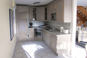 A kitchen with white cabinets, a stove, a sink, and a microwave. - Holiday home with 2 bedrooms (Jemgum-Ditzum)