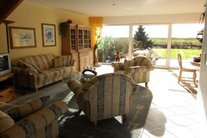 A living room with a sofa set, a cabinet, and a television. - Holiday home with 2 bedrooms (Jemgum-Ditzum)