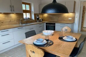 Een moderne keuken met witte kastjes, een houten aanrechtblad en een grote zwarte hanglamp.
