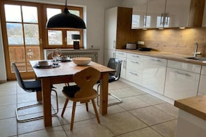 A modern kitchen with a dining table, chairs, and a pendant light. - Holiday apartment with 1 bedroom (Garmisch-Partenkirchen)