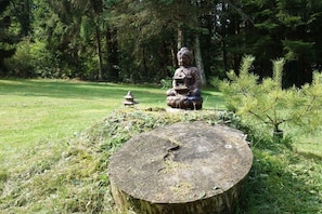 A statue of a seated figure in a natural setting with a tree stump and a small pagoda-like structure nearby. - Holiday apartment with 2 bedrooms (Ludwigswinkel)