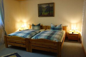A room with two wooden beds, each with a matching headboard and footboard, flanked by bedside tables with lamps. - Holiday apartment with 2 bedrooms (Ludwigswinkel)