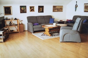 Ett vardagsrum med en grå soffa, ett träbord och en tv som står på ett TV-bord.