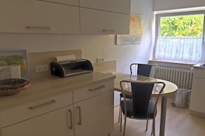 A compact kitchen with a dining area, a toaster, and a window with a view. - Holiday apartment with 2 bedrooms (Geinsheim)