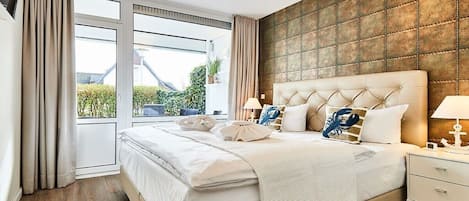 A modern bedroom with a large bed, a view through a sliding door, and a textured wall.