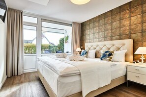 Un dormitorio moderno con una cama grande, vista a través de un ventanal corredero y una pared con textura.