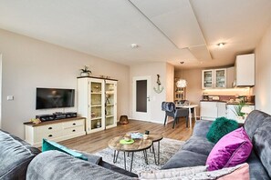 A modern living room with a sofa, coffee table, and entertainment unit. A kitchen is visible in the background. - Tastefully furnished 2-room holiday apartment "Happy Dreams" (Westerland)