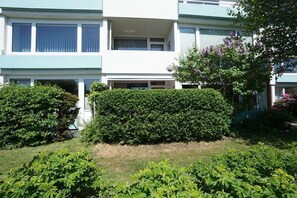 A multi-story residential building with a flat roof, a visible garage door, and a well-maintained hedge in front. - Tastefully furnished 2-room holiday apartment "Happy Dreams" (Westerland)