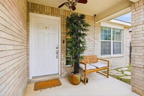 A front porch with a white door, a wooden bench, and a potted plant. - SA Getaway Nr Sea World | Yard BBQ Games WiFi Pets (San Antonio)