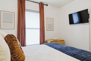 Ein Schlafzimmer mit einem Bett, einem Fernseher und zwei gerahmten Bildern an der Wand.