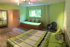 Ein Zimmer mit einem Bett, einem Sessel, einem Fenster und einem Kleiderschrank.