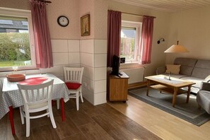 Ein gemütliches Wohnzimmer mit einer Couch, einem Esstisch mit Stühlen, einem Couchtisch und einem Fernseher.